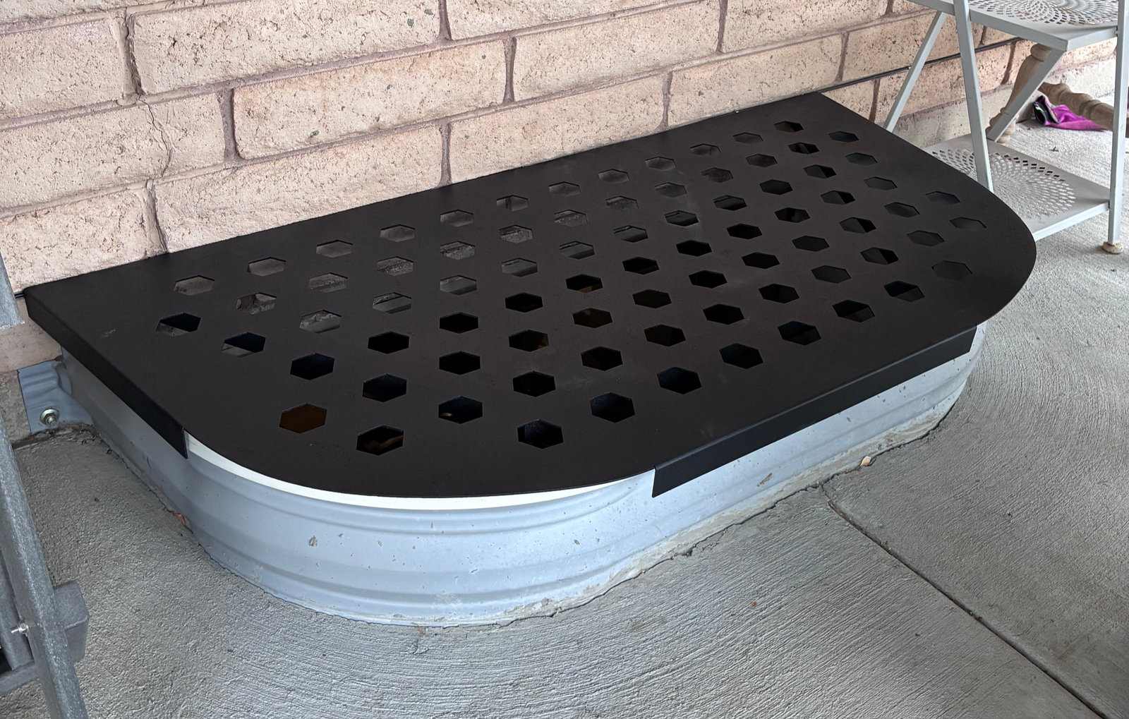 Custom laser-cut window well cover installed over a galvanized well